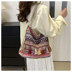 Detail of bohemian shoulder bag showing intricate ethnic embroidery and colorful tassels