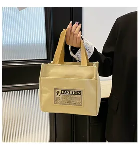 Détail du sac cabas en toile minimaliste avec anses contrastées et étiquette tissée