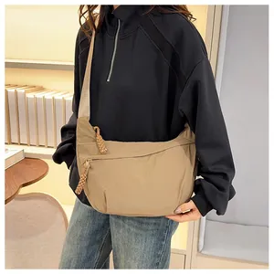 Detail of khaki nylon crescent bag featuring wide shoulder strap and woven rope zipper pull