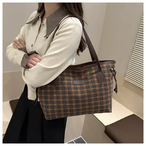 Detail of vintage plaid tote bag featuring leather shoulder straps and classic woven pattern