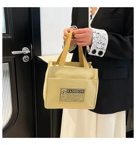 Gros plan sur un sac cabas en toile beige avec anses tissées et étiquette mode