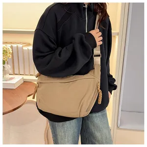 Model wearing a khaki crescent nylon crossbody bag with adjustable wide strap for daily use