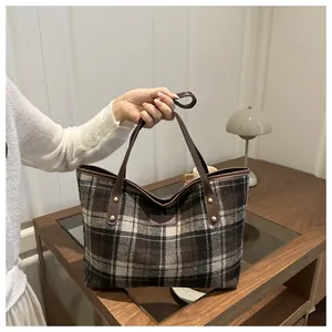 Macro view of plaid woolen tote bag texture with brown leather strap and golden rivet detail