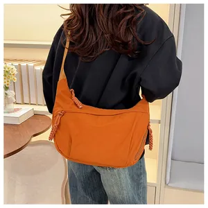Detail shot of a burnt orange nylon crescent bag worn across a black sweatshirt