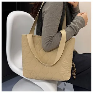 Detail of beige quilted tote bag showing wave-pattern texture and wide fabric strap