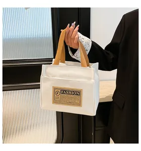 Détail du sac en toile blanche avec poignées tressées brunes et écusson vintage
