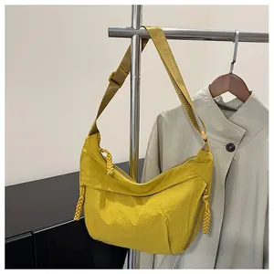 Detail of yellow nylon dumpling bag with woven zipper pulls on silver metal hanger