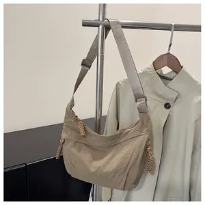 Detail of khaki nylon crescent bag with woven zipper pull hanging on a metal rack