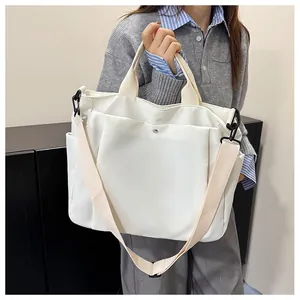 Détail du cabas en toile crème avec poches latérales et bandoulière réglable