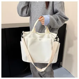 Détail d'un sac cabas blanc en toile avec bandoulière réglable et poches latérales