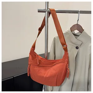 Detail of orange nylon crescent bag with adjustable wide strap and woven rope zipper pull