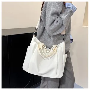 Détail d'un sac cabas en nylon blanc avec poches latérales et bandoulière sur un modèle