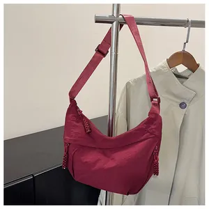 Detail of burgundy nylon dumpling bag with pleated texture and adjustable strap