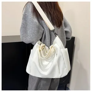 Détail d'un grand sac cabas blanc en toile avec une large bandoulière en tissu réglable