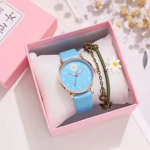 Detalle de reloj de margarita azul claro y pulsera tejida en caja de regalo rosa