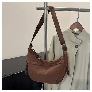 Close-up of brown nylon crescent bag with adjustable wide strap on a metal hanger