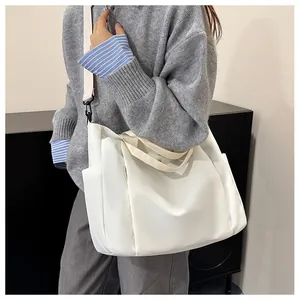 Détail du sac fourre-tout en toile blanche avec poche latérale et large bandoulière
