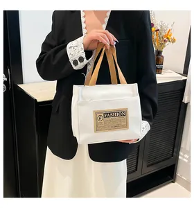 Détail du sac fourre-tout en toile blanche avec anses brunes et étiquette vintage