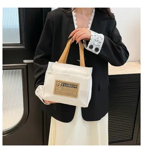 Détail d'un sac cabas en toile blanche avec poignées marron et écusson de mode vintage