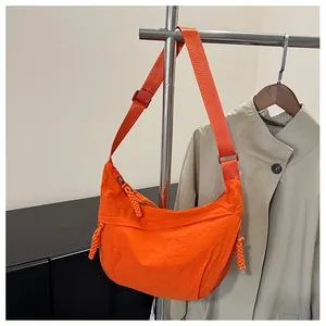 Detail of orange nylon dumpling bag with adjustable strap and woven zipper pullers
