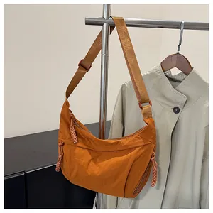 Detail of caramel nylon crossbody dumpling bag with woven rope zipper and wide strap
