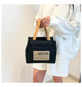 Détail du sac cabas en toile noire avec anses kaki et écusson de mode