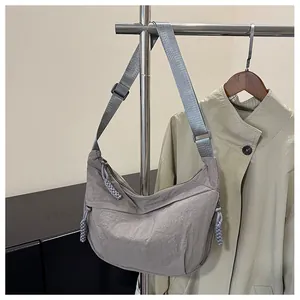 Detail view of grey nylon crescent bag with adjustable strap and knotted zipper pulls
