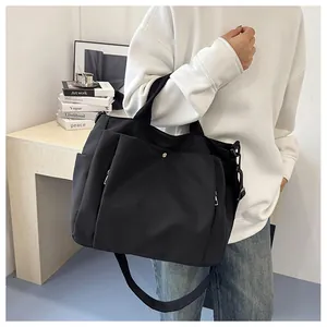 Détail d'un grand sac cabas en toile noire avec poche zippée et bandoulière réglable