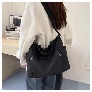 Détail d'un grand sac fourre-tout noir en nylon avec bandoulière et poche zippée latérale
