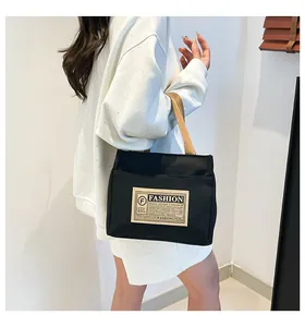 Détail du sac fourre-tout en toile noire avec étiquette mode et poignées couleur kaki