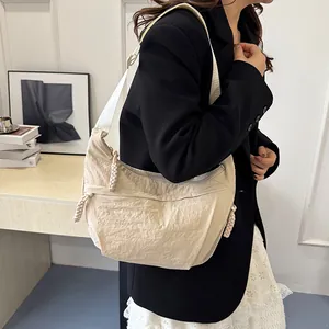 Minimalist cream nylon dumpling bag with adjustable shoulder strap worn by a model