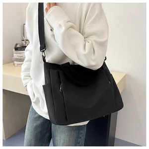 Vue latérale d'un grand cabas en nylon noir avec bandoulière réglable sur modèle