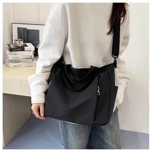 Détail du grand sac à bandoulière noir avec poches zippées et larges bretelles