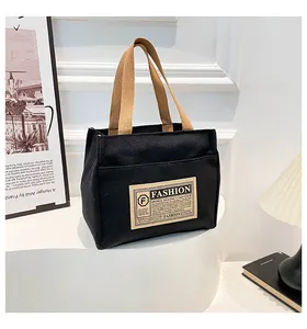 Détail du sac cabas en toile noire avec anses marron contrastées et patch tendance