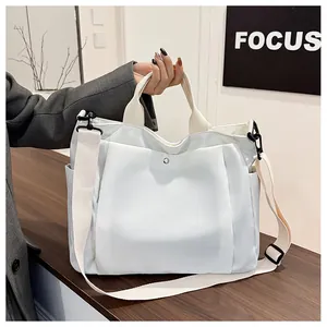 Détail d'un grand sac cabas en toile blanche avec bandoulières beiges sur table bois