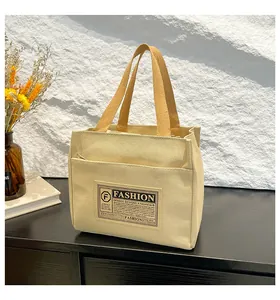 Détail du sac fourre-tout en toile beige avec sangle jaune et étiquette tissée mode