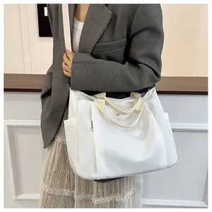 Détail du grand sac cabas en toile blanche avec poches latérales et sangles larges
