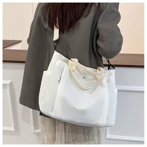 Détail d'un grand sac cabas en toile blanche porté à l'épaule sur un mannequin