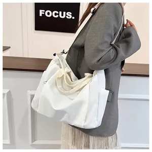 Grand sac fourre-tout en nylon blanc sur un modèle avec bandoulière réglable et poches