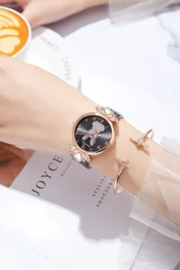 Dettaglio dell'orologio rosa con coniglio e bracciale ad ape con caffè di sfondo