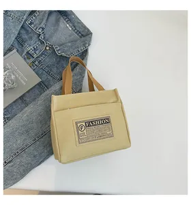 Gros plan détaillé d'un sac en toile beige avec écusson rétro et anses en sangle foncées