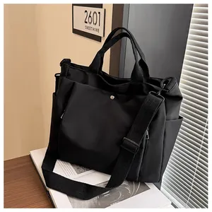 Détail du grand sac cabas en toile noire avec bandoulière réglable et poche latérale