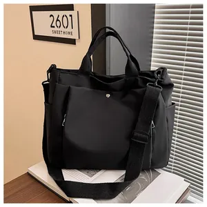 Détail d'un grand sac cabas noir en toile avec boucle métallique et bandoulière large