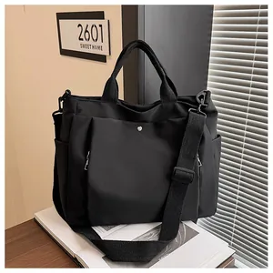 Détail du sac fourre-tout en toile noire avec bandoulière large et poche magnétique