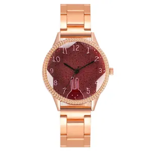 Détail d'une montre en or rose avec cadran rouge foncé et illustration de lapin blanc