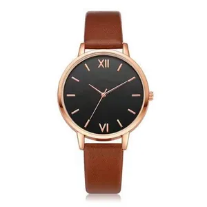 Detail of rose gold quartz watch with black dial and textured brown leather strap