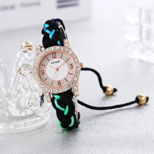 Nahaufnahme einer rotgoldenen Strass-Uhr mit farbenfroh geflochtenem Armband