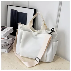Détail du sac cabas blanc montrant la poche à rabat avec boucle magnétique argentée