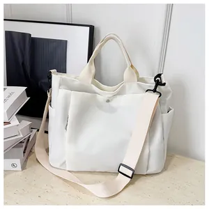 Détail du sac cabas en toile blanc cassé avec bandoulière réglable et grande poche avant