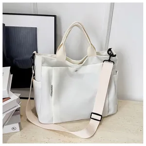 Vue détaillée du sac fourre-tout en toile crème avec bandoulière et poche à bouton métal
